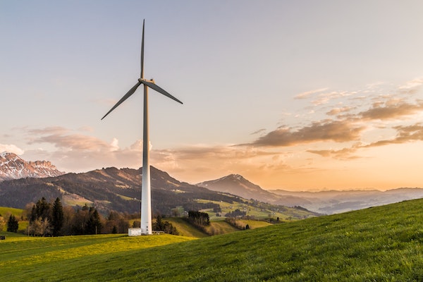 A wind turbine stands amid rolling hills.