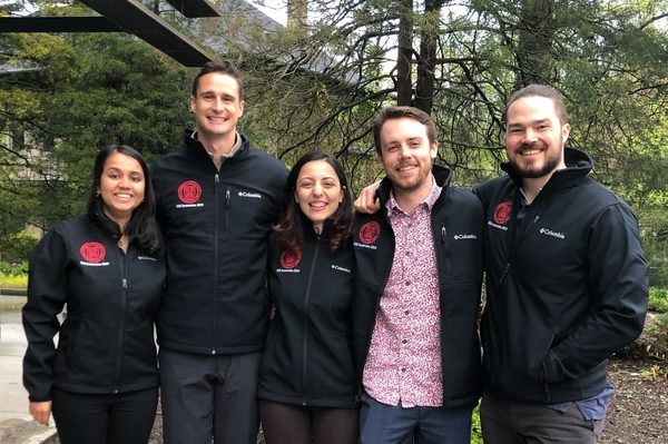 Five students pose for a photo wearing branded jackets.