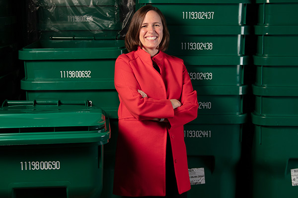 Christina Keller standing in front of a stack of green plastic bins