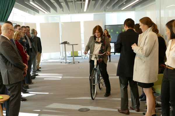 Linda Canina rides a bike in a demonstration at Deloitte