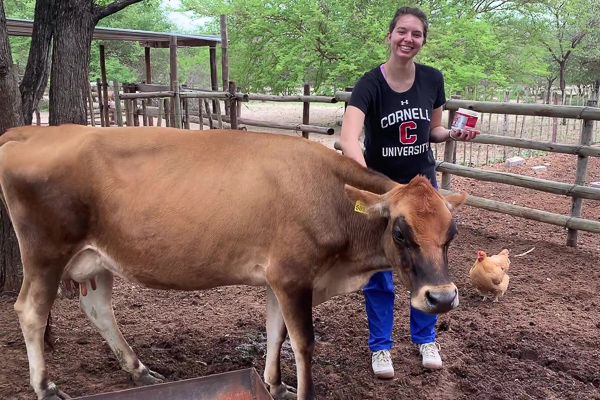 Emma smiling and petting a cow