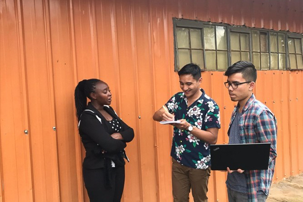 Two students speaking with a woman outdoors