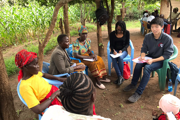 A group of people sits on the ground outdoors