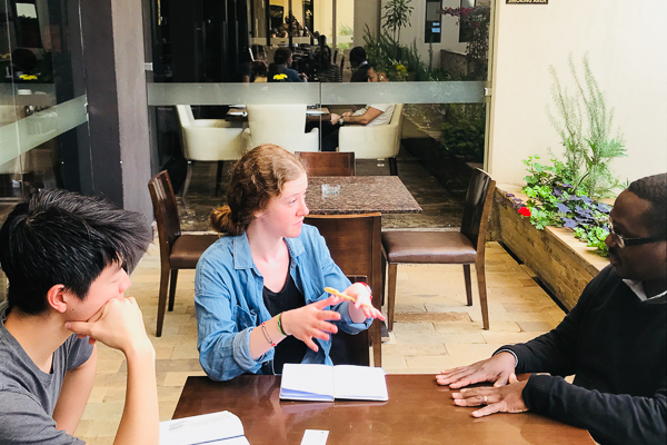 Three people speaking around a table and taking notes