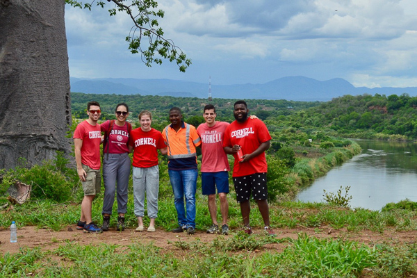 Six people stand with the water behind them