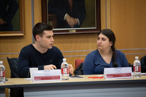 A male and a female student sit behind a table.