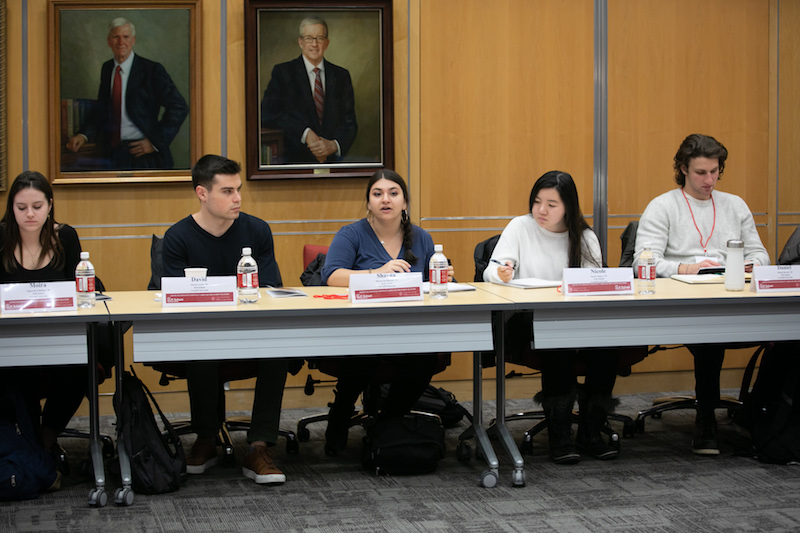 Four students sit behind a table.