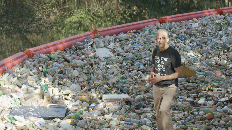 Fisk stands in an enormous pile of plastic waste