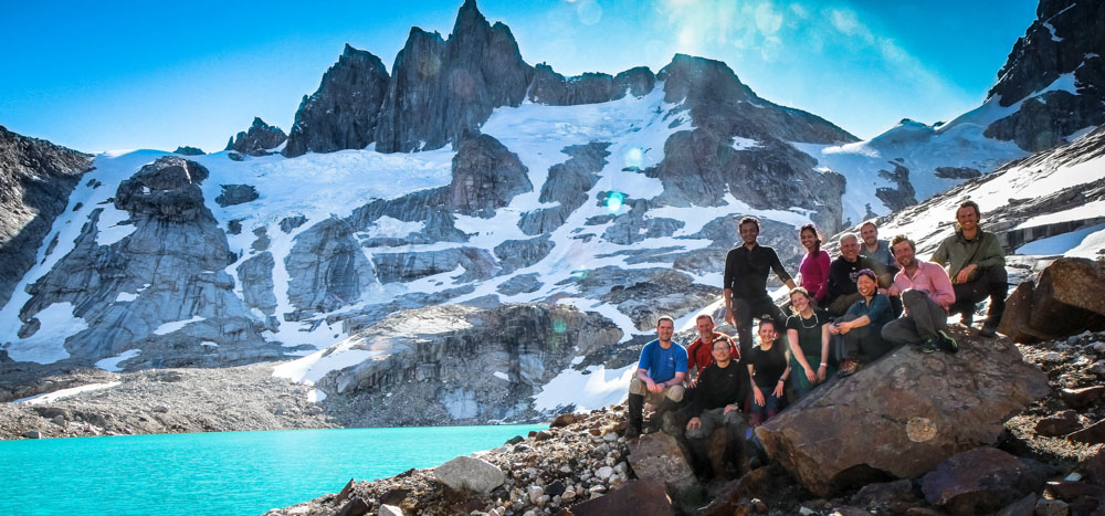 A group of students stands on a mountain side with a river in the background