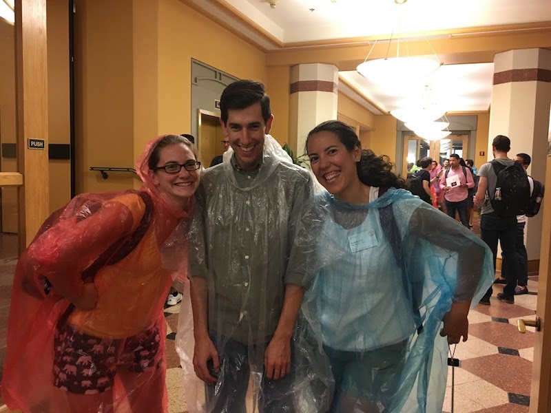 3 students wearing plastic ponchos stand together