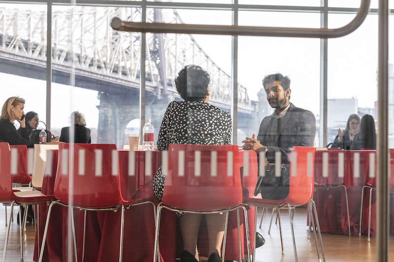 A student and mentor seated at a table in a Cornell Tech meeting space