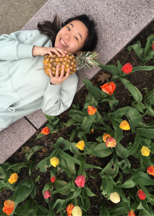 Nicole Lai sitting among tulips holding a pineapple