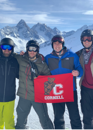 Colin and classmates holding a Cornell flag on a mountain