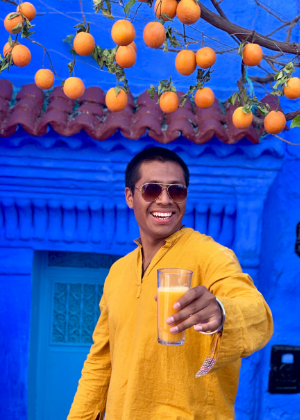 Eric Garcia standing under an orange tree holding orange juice