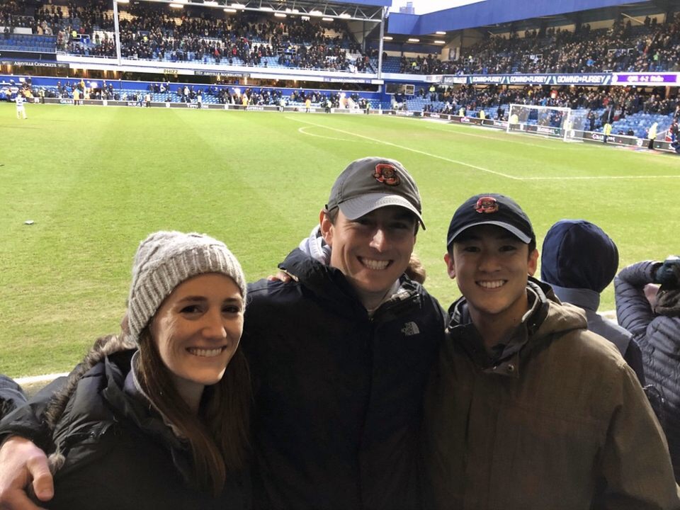 Three students pose for a photo at a soccer match