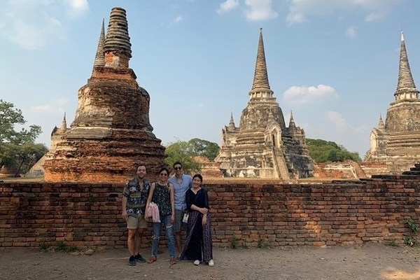 Four students stand in front of a large temple in Thailand