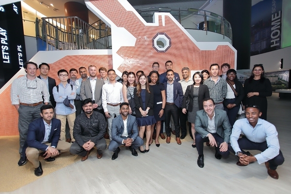 A large group of students stands in a company's lobby