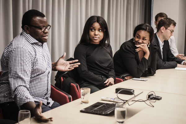 Students and others sit along a conference table