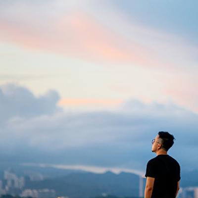 Man on mountain looking out at city below