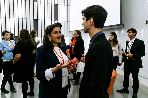 photo of people in business attire mingling and talking to one another in a large, light-filled room