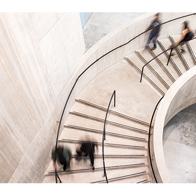People walking down a curved, concrete staircase