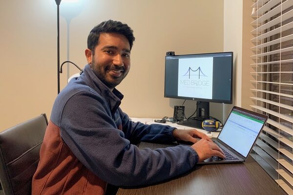 A picture of Rahul Singh sitting at his desk in front of a computer, working from his office