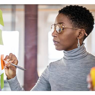 Standing woman writing on a sticky note