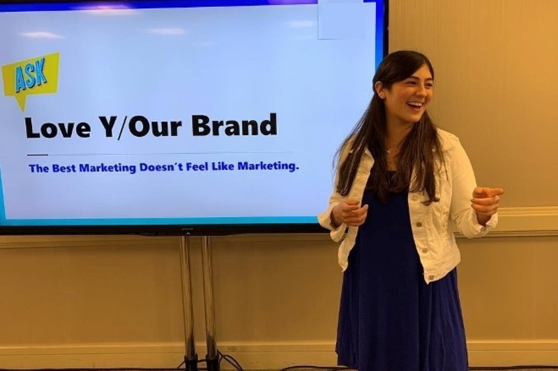 The author stands in front of a large screen giving a presentation. 