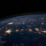 photo of part of the earth's globe from space showing bright clusters of lights (cities) interconnected with lighter streams or veins of lights