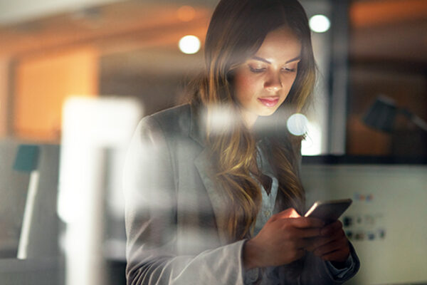 An employee checks her smart phone for employer updates.