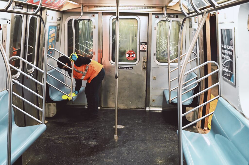 Essential worker in PPE sanitizing a subway car