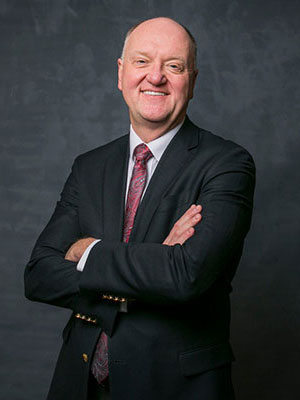 portrait of Andrew Karolyi standing with folded arms