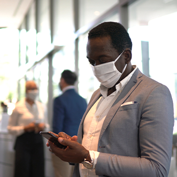 Man in mask looking at mobile device