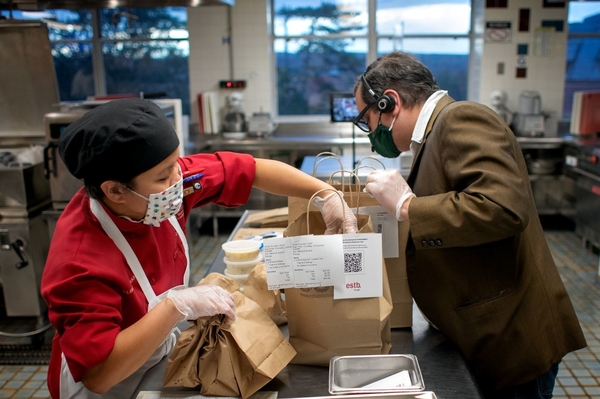 Two Statler Hall employees work together to pack to-go orders from Establishment, a student-run restaurant.