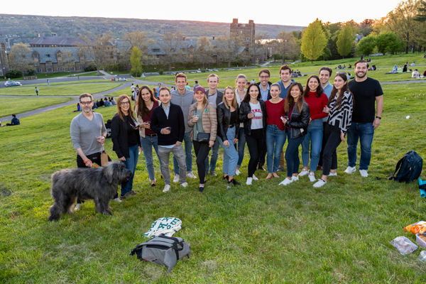 group of students posing for a photo on libe slope at dusk