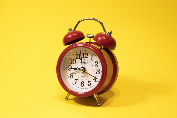 an image of a bright red clock on a yellow background