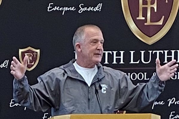 Bill Dully speaking at a podium gesturing with arms outstreched