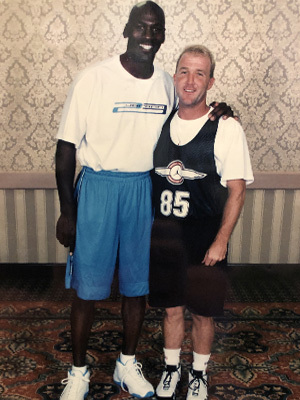 Bill Dully standing next to a much taller Michael Jordan, both wearing long basketball shorts and T-shirts