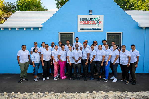 Bermuda Molecular Diagnostics & Research Laboratory staff (24 people)about standing in front of a sky-blue building
