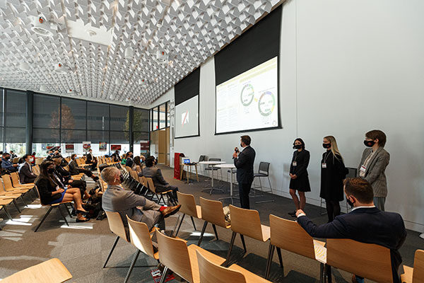 Students dressed in professional attire addressing a lecture hall audience