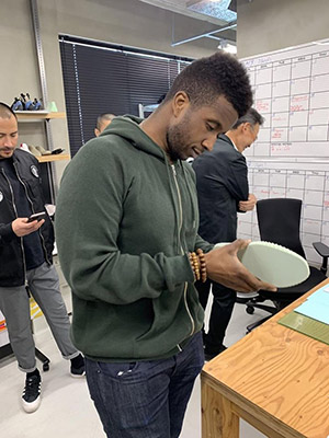 Aaron Sebron standing while holding and examining an athletic shoe with a couple of other people in the background 