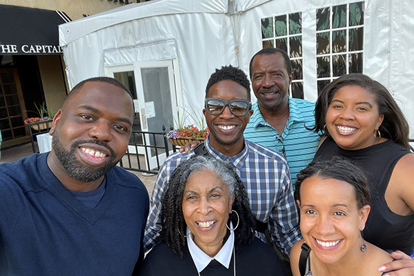 Aaron Seabron surrounded by five adults, all smiling, in front of the entrance to a restaurant