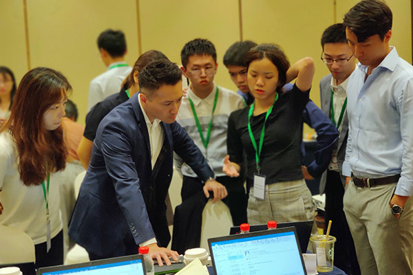 Steve Cheng, center, surrounded by your adults in business attire, all standing and looking down at a computer screen.