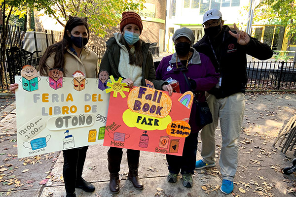 Morgan Jones with three other people on a city street holding Fall Book Fair posters