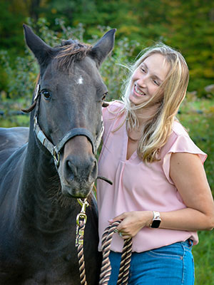 Anna Richards standing with her arm around the neck of her horse, who is looking at the camera