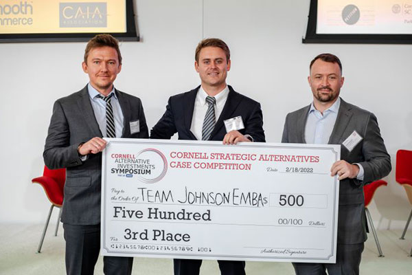 3 men in suits standing and holding an oversized check for $500
