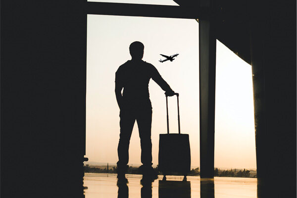 person with suitcase watching a plane take off
