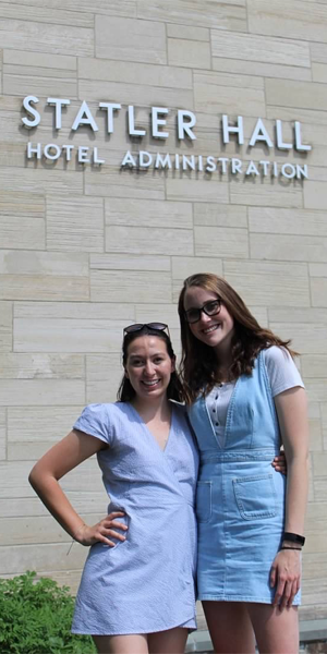 Hannah MacDonald and Kyra Roach smile together in front of Statler Hall