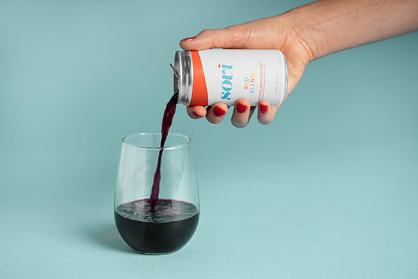 photo of someone's hand pouring a glass of red wine from a Sovi can