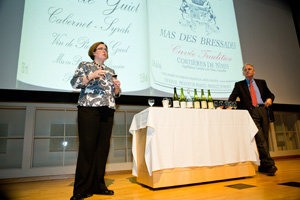 professor stands on stage with bottles of wine